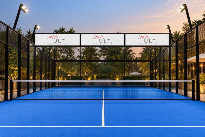 A floodlit padel court at dusk, part of the WAULT sports and fitness venue network